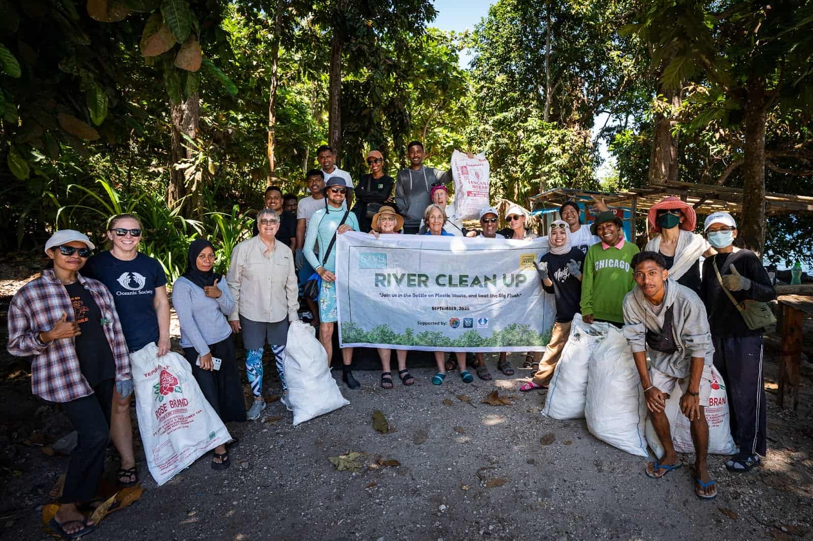 Volunteers participating in a community cleanup in Alor, collecting trash along the shoreline with Planet Deep and Trash Hero.