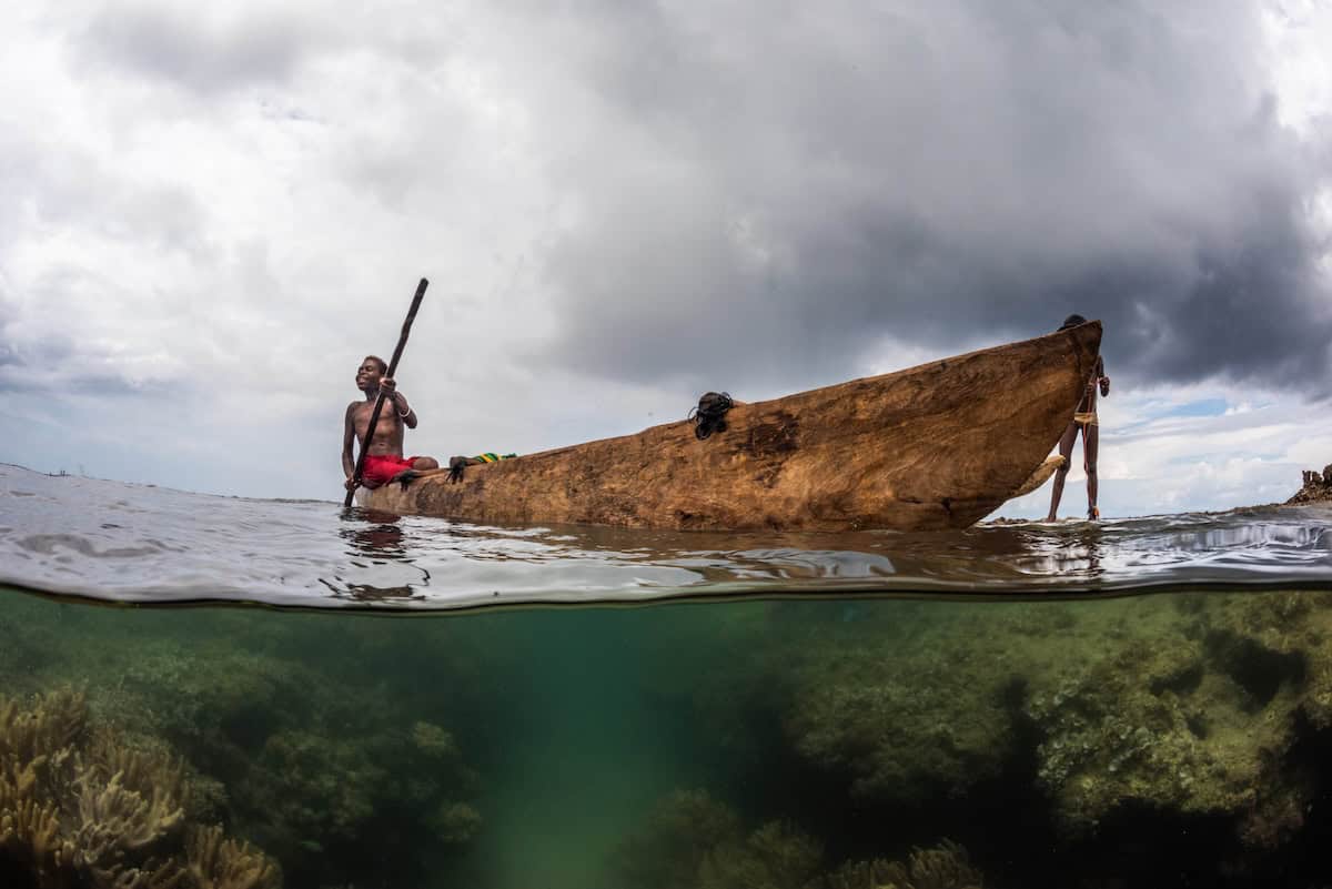 Fijian fisherman in a traditional wooden canoe, highlighting the challenges of fishing as coral reef decline reduces local fish populations.