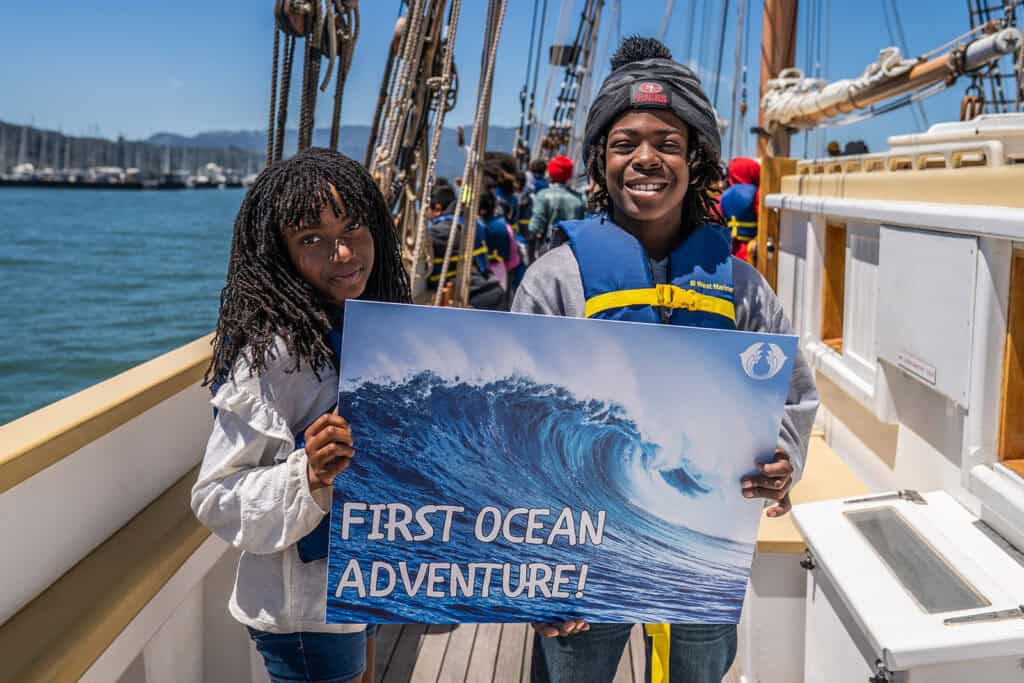 children hold a sign reading "first ocean adventure"