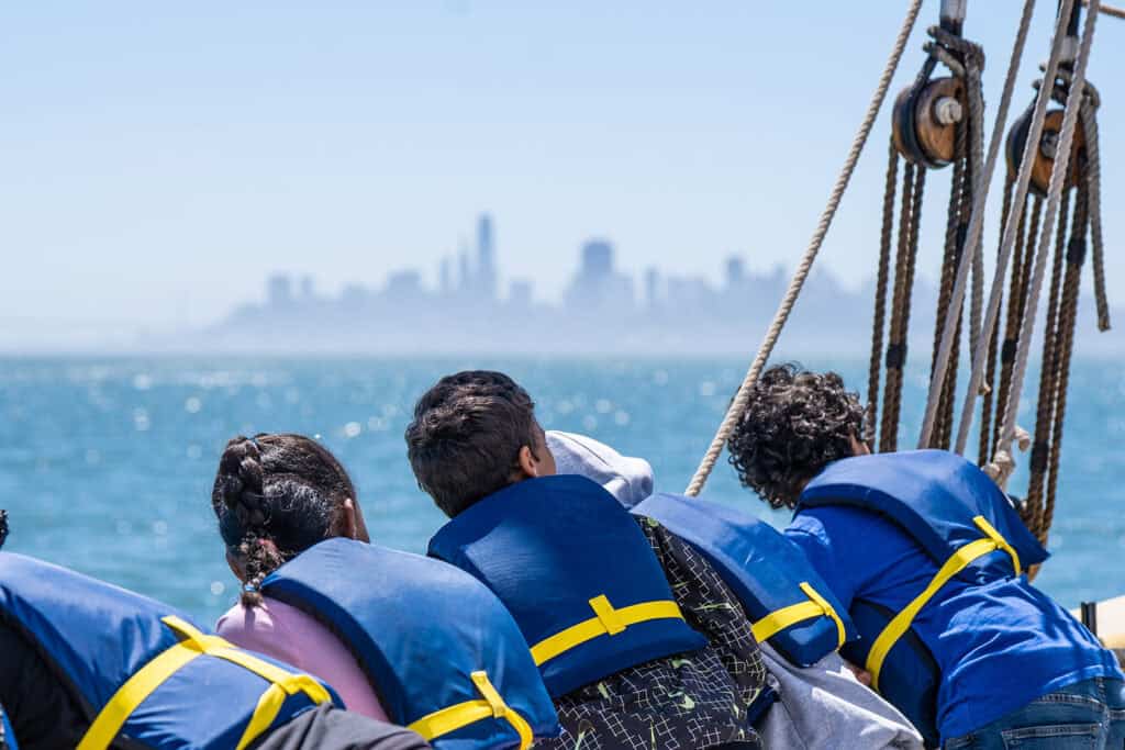 students on a boat look at the san francisco skyline