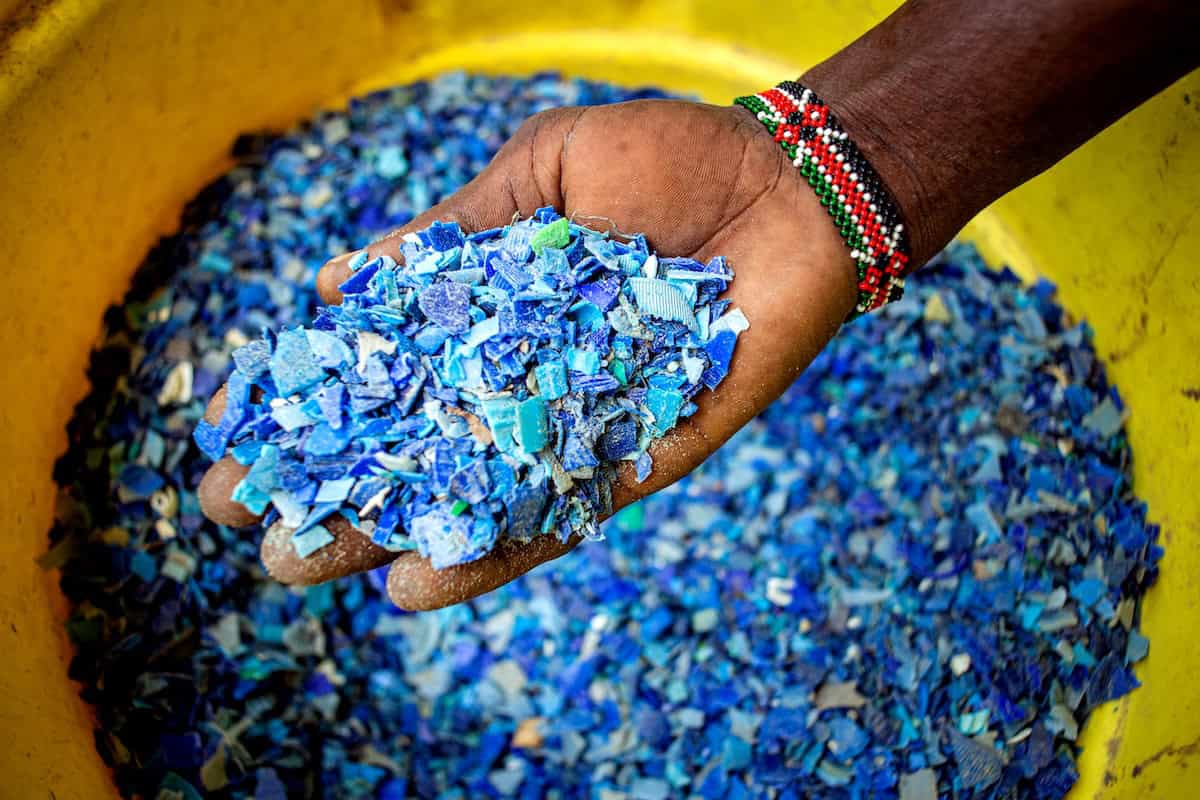 A participant at Eco-World Watamu displays shredded plastic flakes produced from collected beach and marine debris, representing a key step in the Watamu Marine Association's circular economy initiative that converts waste into marketable resources while reducing pollution in Kenya's coastal ecosystems.