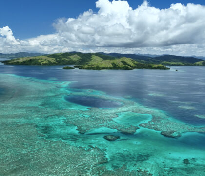 Aerial view of Rainbow Reef clear waters and mountains in Fiji
