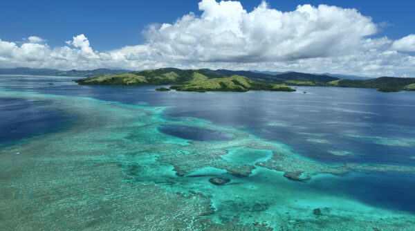 Aerial view of Rainbow Reef clear waters and mountains in Fiji