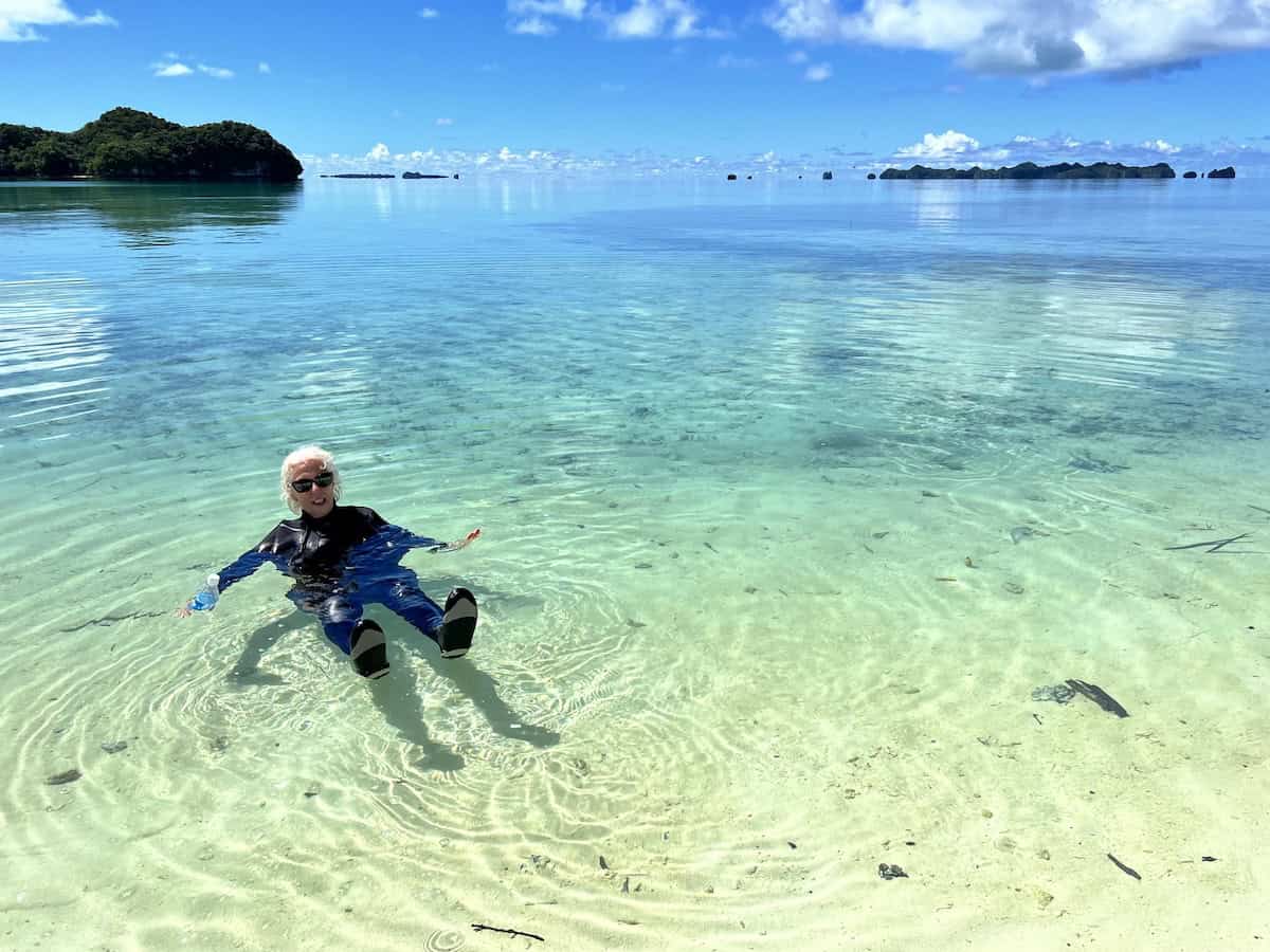 Woman swimming in clear tropical ocean water with small sharks.