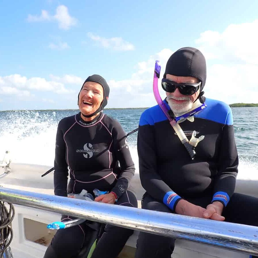 Two snorkelers in wetsuits standing on a boat, ready for a snorkeling adventure in Jardines de la Reina, Cuba.
