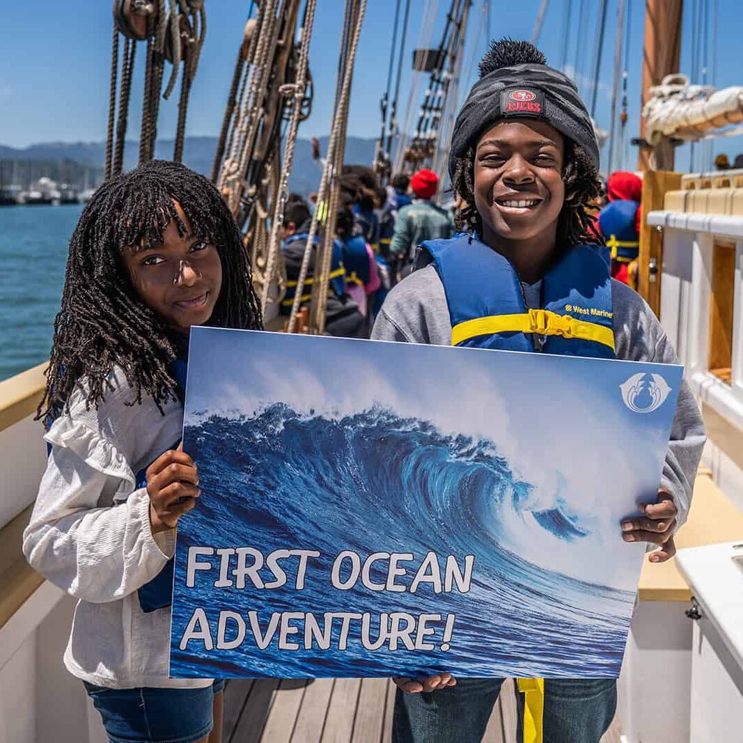 children hold a sign reading "first ocean adventure"